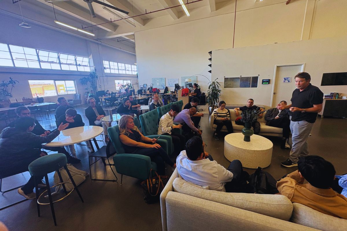 Frontiers Day wide shot of the SOSV San Francisco lounge with delegates seated across teal armchairs and sofas listening to the host