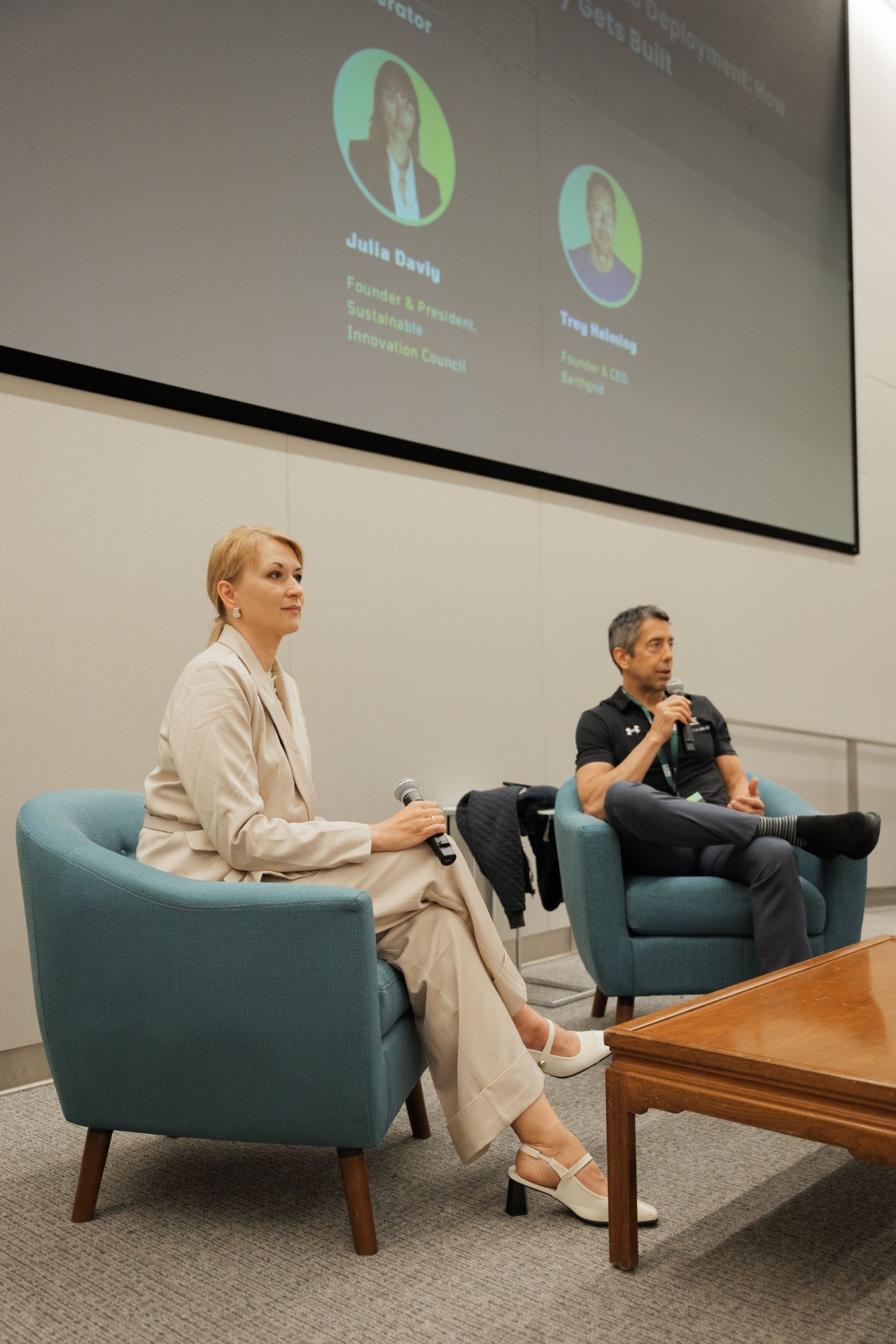 Julia Daviy moderating the Capital Day fireside conversation with Troy Helming, Founder & CEO of Earthgrid, beneath the speaker slide