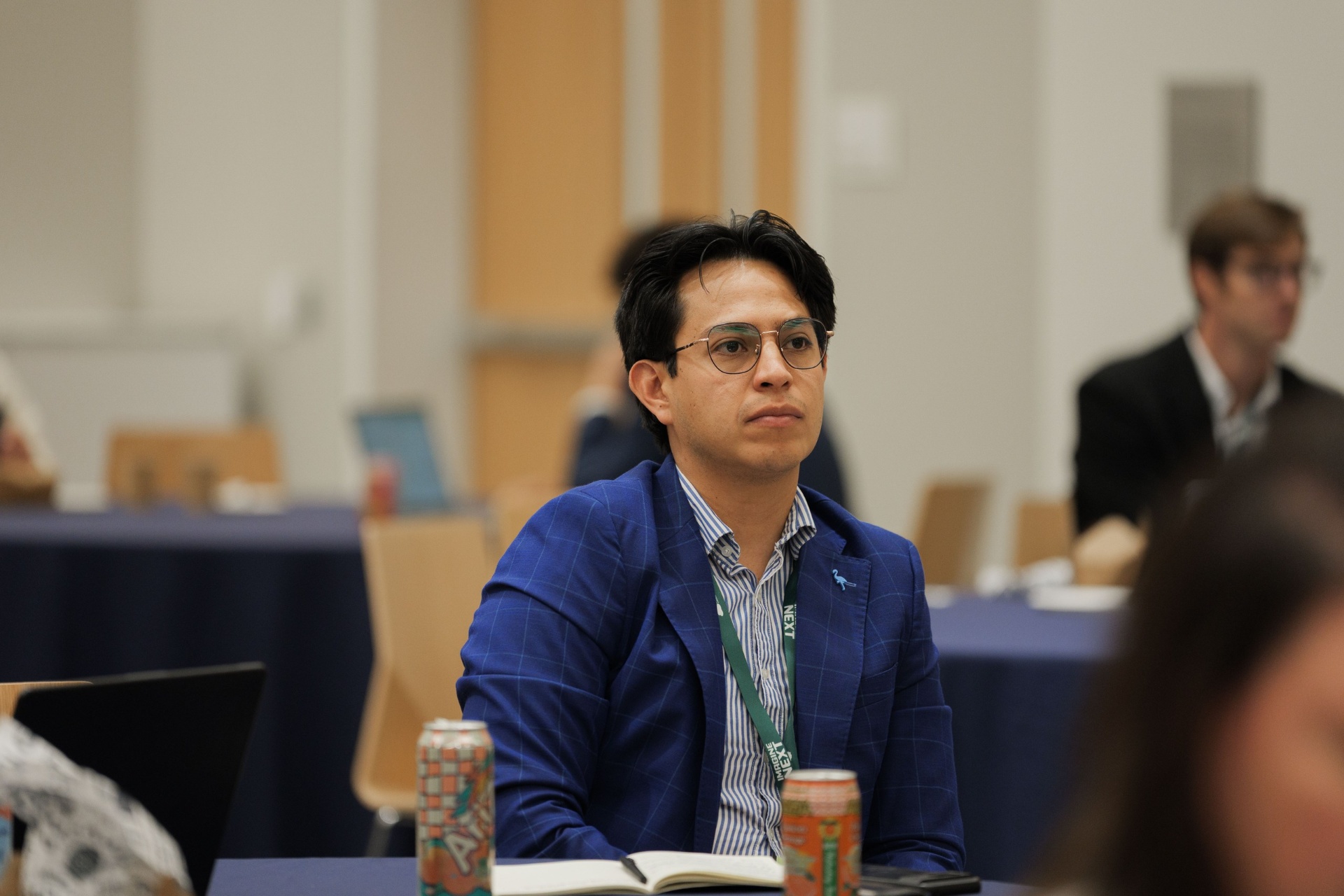 Capital Day delegate in a blue windowpane blazer listening attentively during a session at UC Law SF