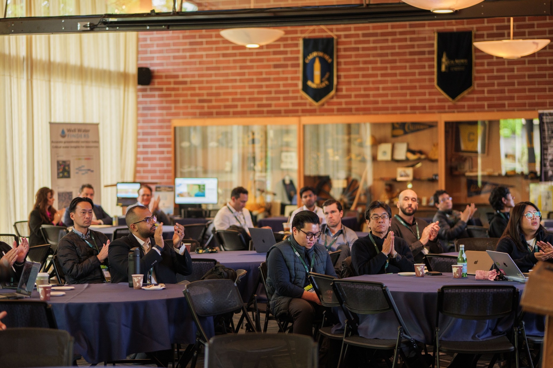 Audience applauding at the round tables in the Alumni House