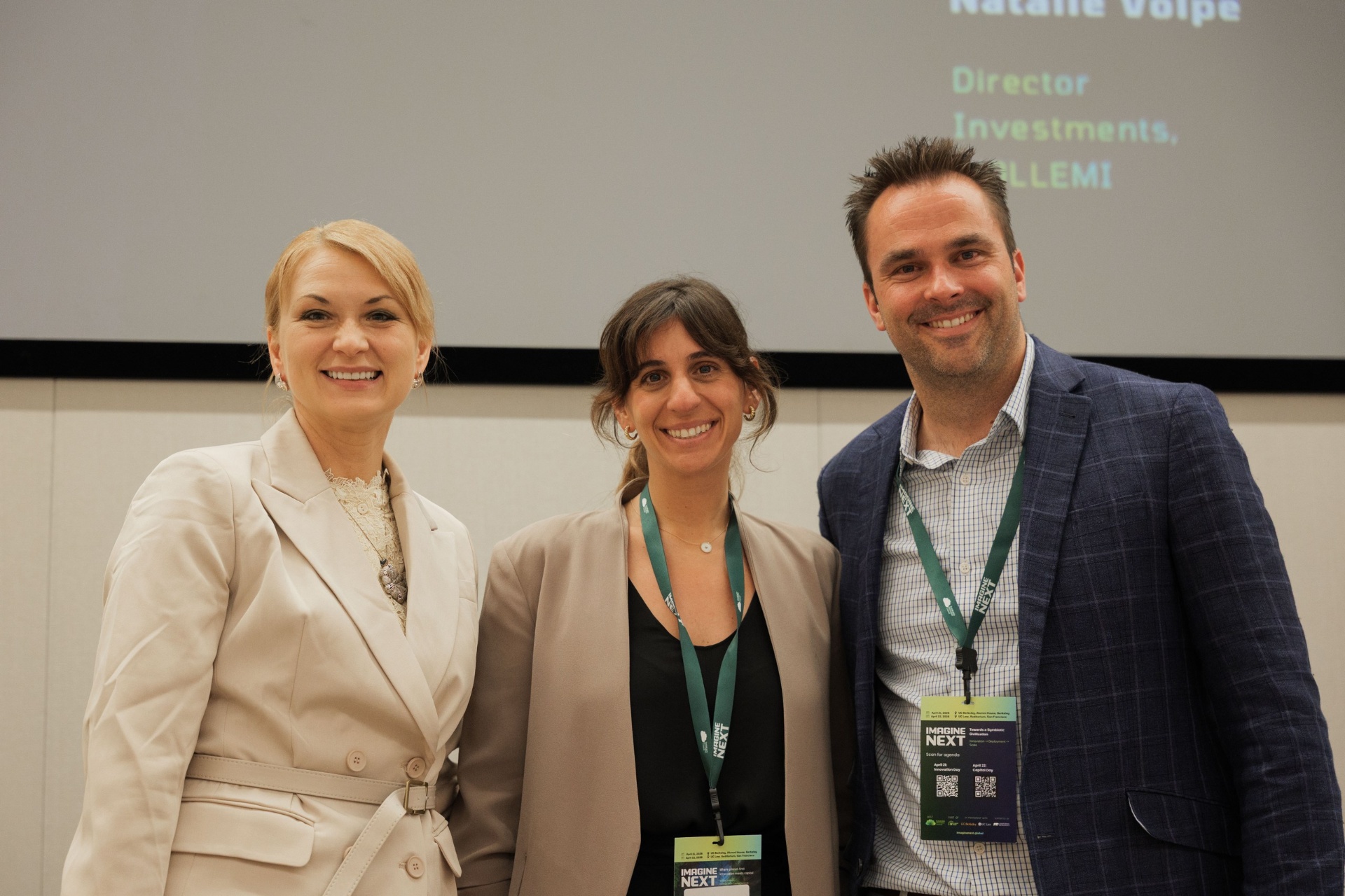 Natalie Volpe of WOLLEMI smiling with two Imagine Next jurors on the Capital Day stage at UC Law SF