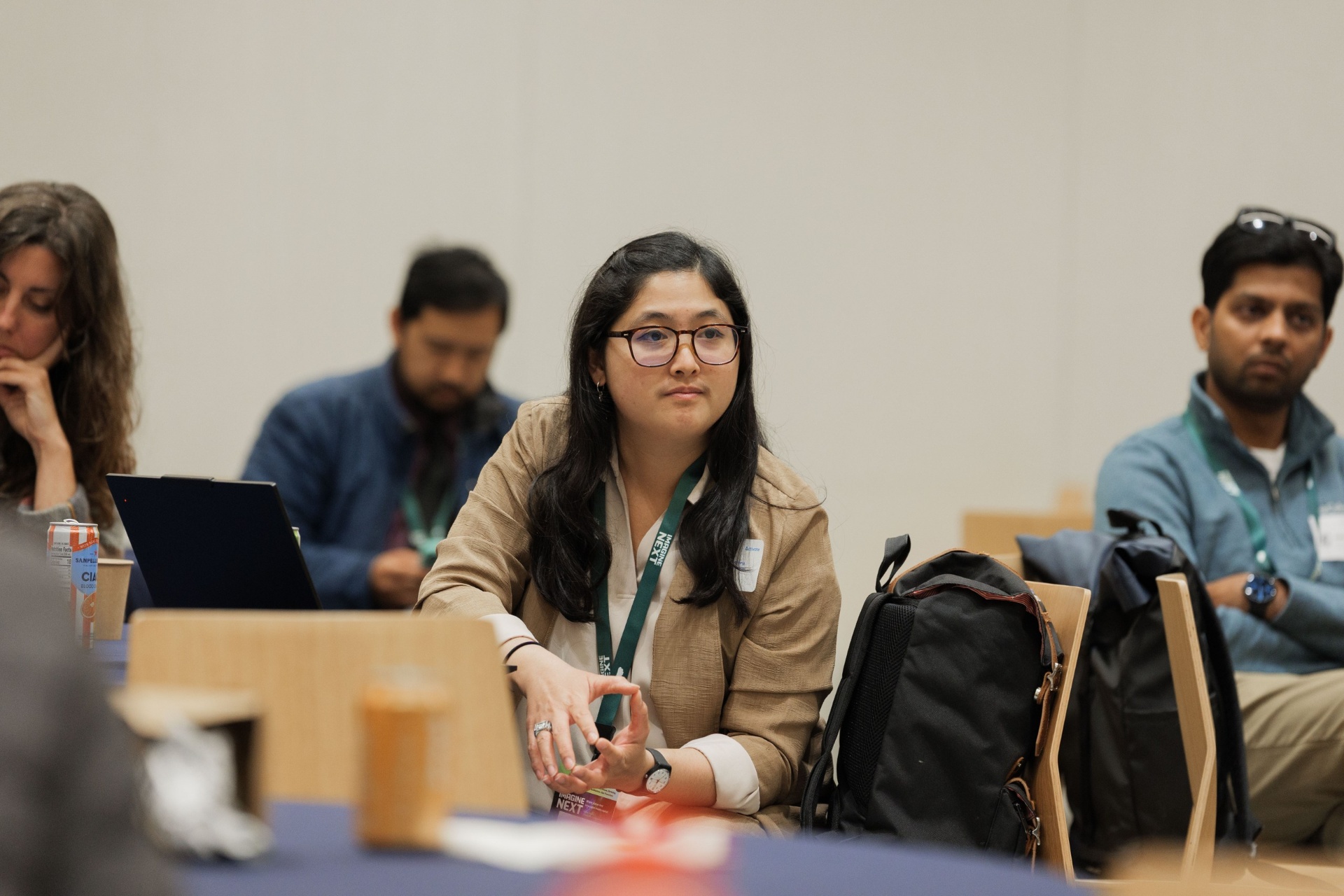 Capital Day delegate in glasses and a tan blazer listening attentively from the audience during a session at UC Law SF