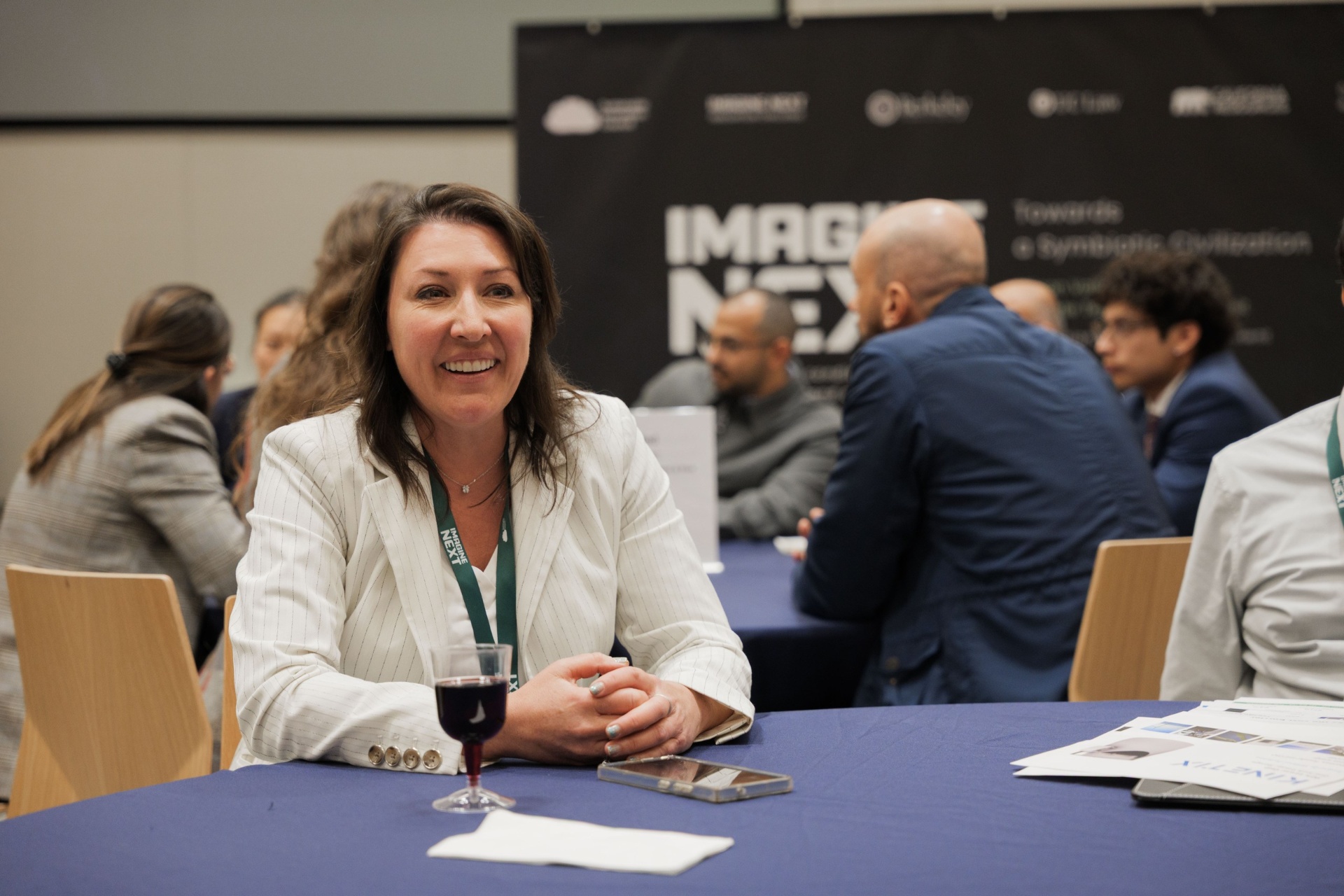 Portrait of an investor smiling during the Capital Day Curated Capital Matchmaking Sessions beneath the Imagine Next 'Towards a Symbiotic Civilization' banner