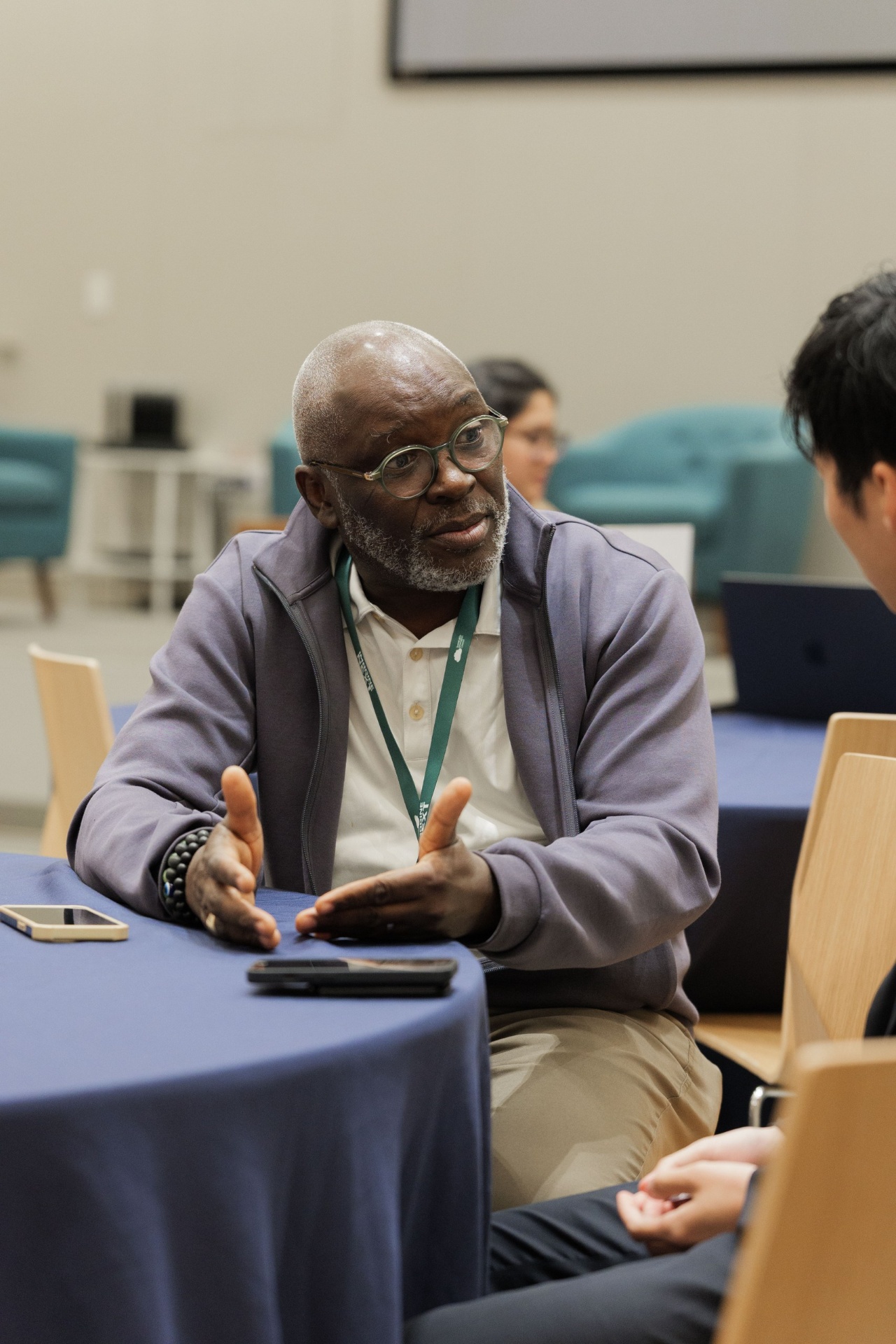 Portrait of a delegate in a grey jacket and round glasses gesturing while speaking during the Capital Day Curated Capital Matchmaking Sessions at UC Law SF
