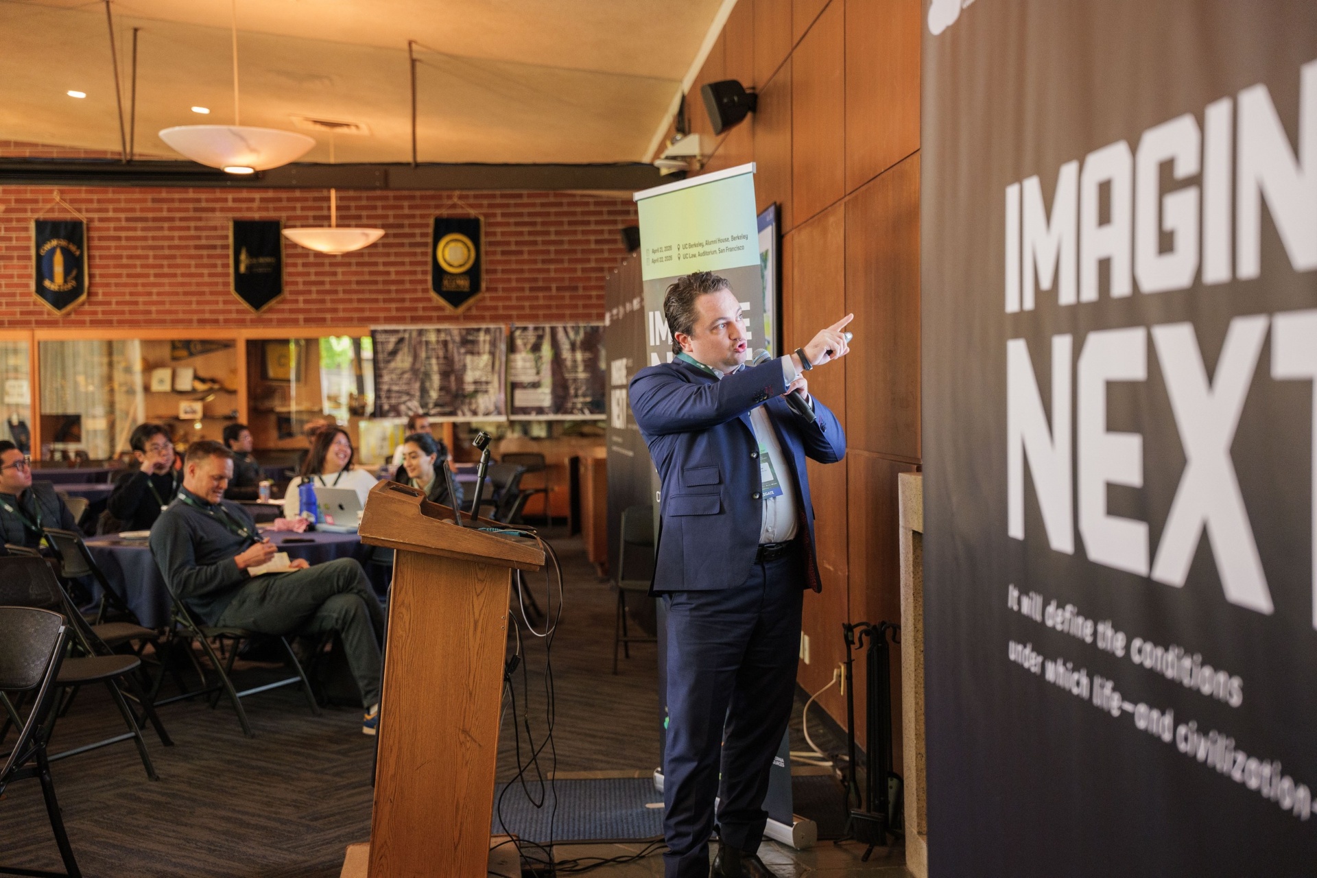 Founder pitching with the Imagine Next banner backdrop