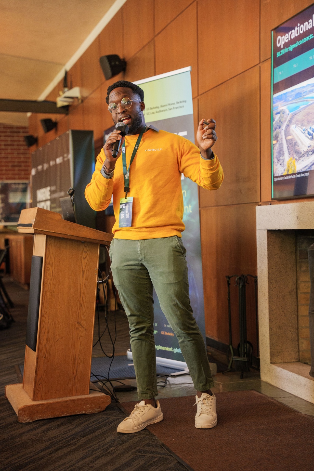 Airbuild founder pitching in orange sweater at the podium
